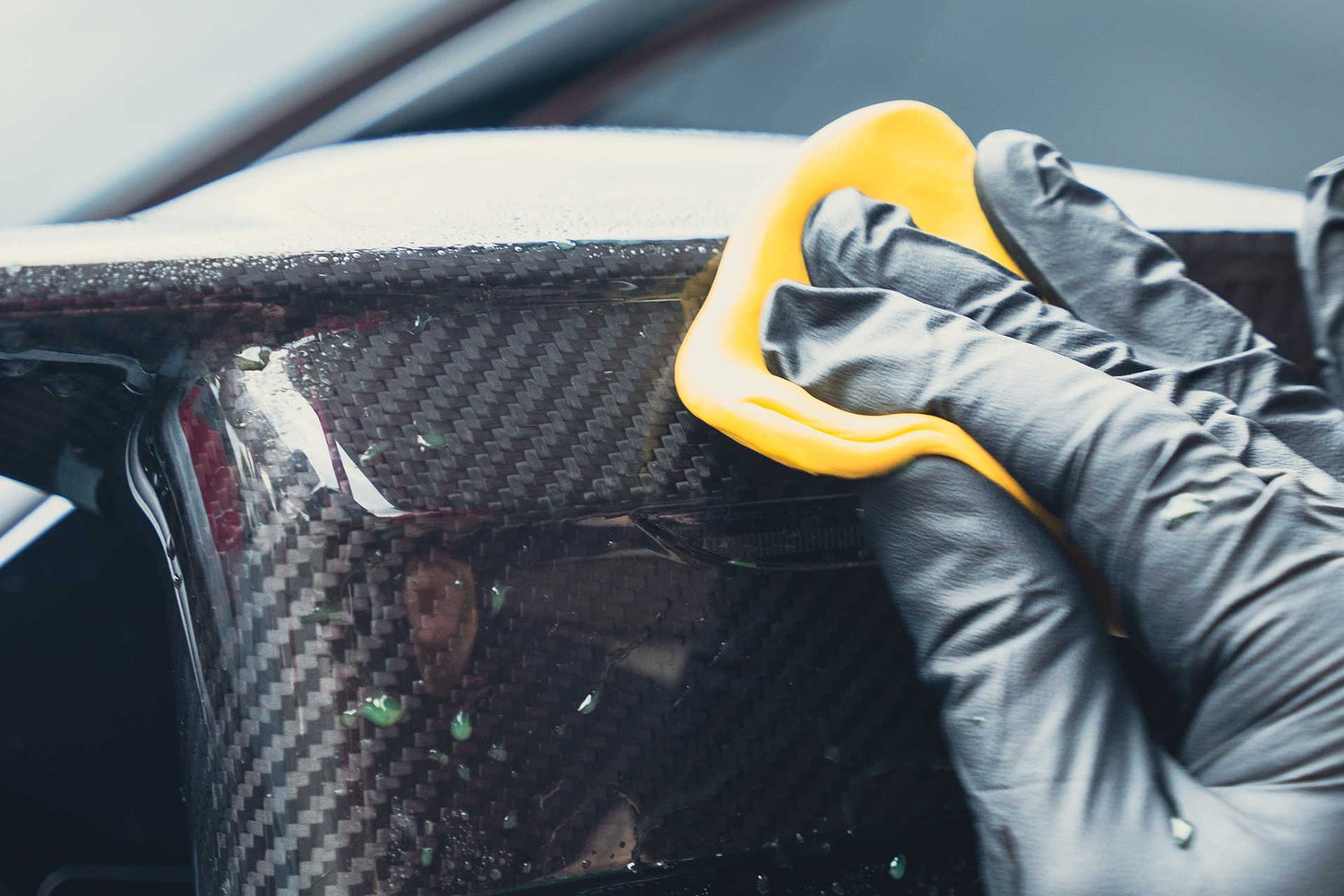 detailer using clay bar to decontaminate carbon fiber mirror cap