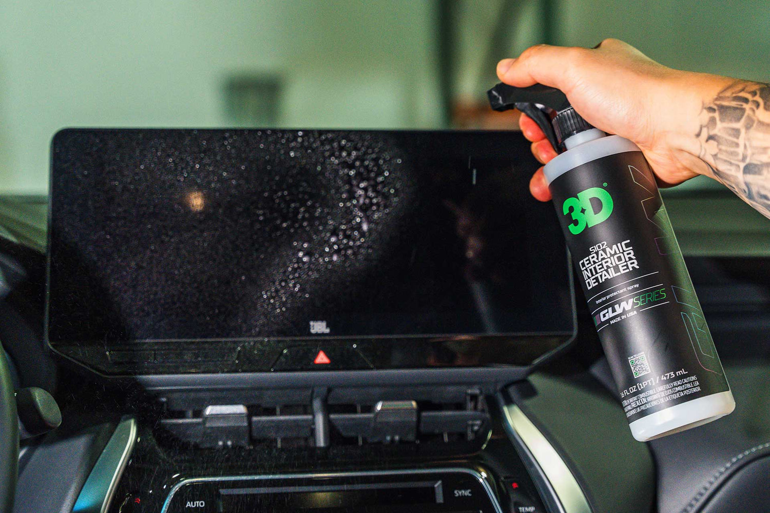 person spraying ceramic interior detailer on infotainment screen