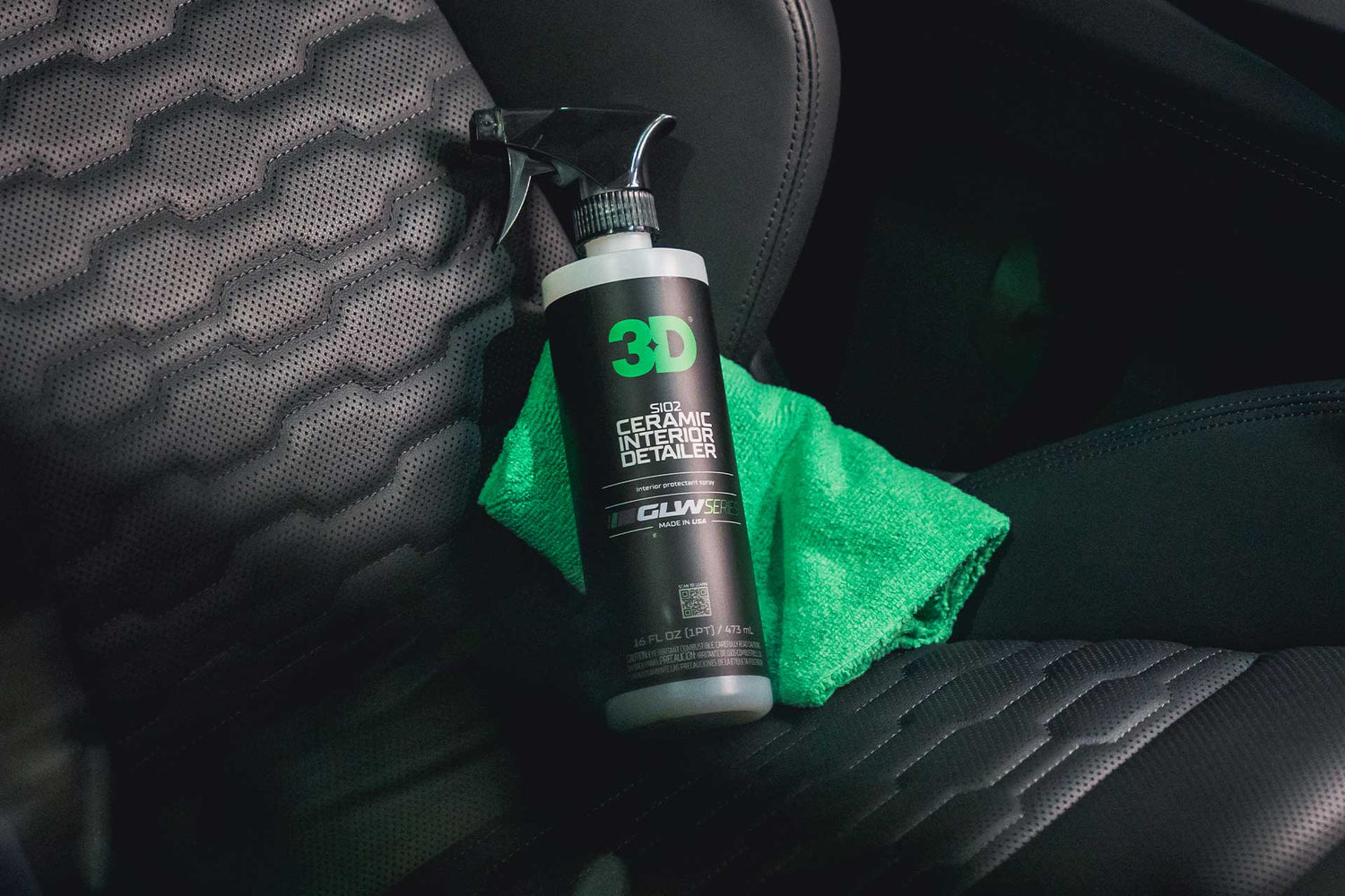 bottle of ceramic interior detailer and green microfiber towle on car seat