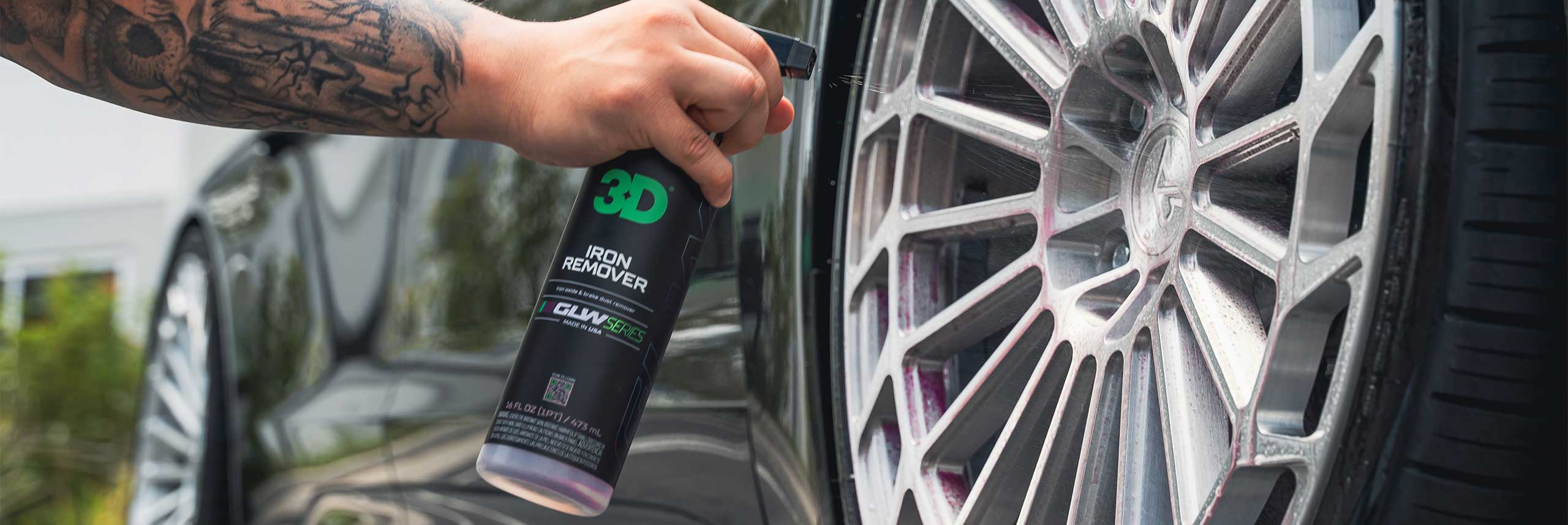 person spraying iron remover on silver aftermarket wheels