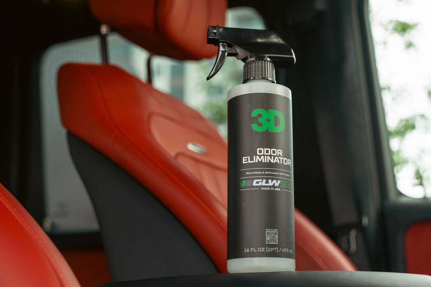 bottle of odor eliminator in front of red leather car seats